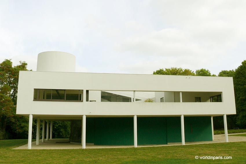 23 Amazing UNESCO Sites in Europe, Off the Beaten Track 24 Villa Savoye a modern looking building with white rectangular box with rectangular windows supported on 5 thing columns with a round white tower in the left hand background.