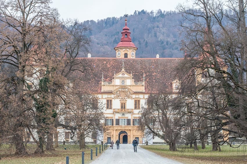 23 Amazing UNESCO Sites in Europe, Off the Beaten Track 19 Graz show an avenue flanked by trees in winter leading to a large building with a bell tower