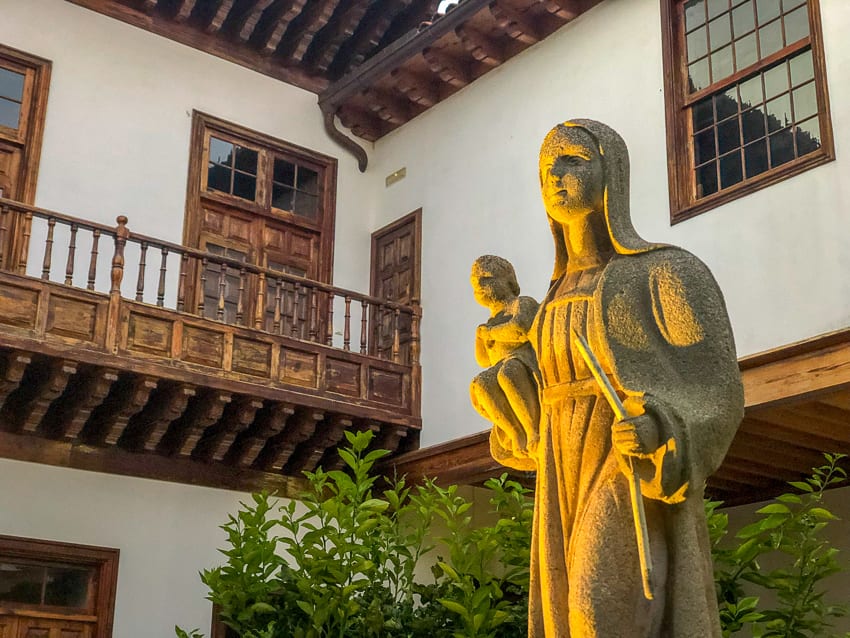 23 Amazing Unesco Sites In Europe, Off The Beaten Track 7 Stone statue of Madonna with Christ lit from underneath in front of a white building with wooden verandah and windows