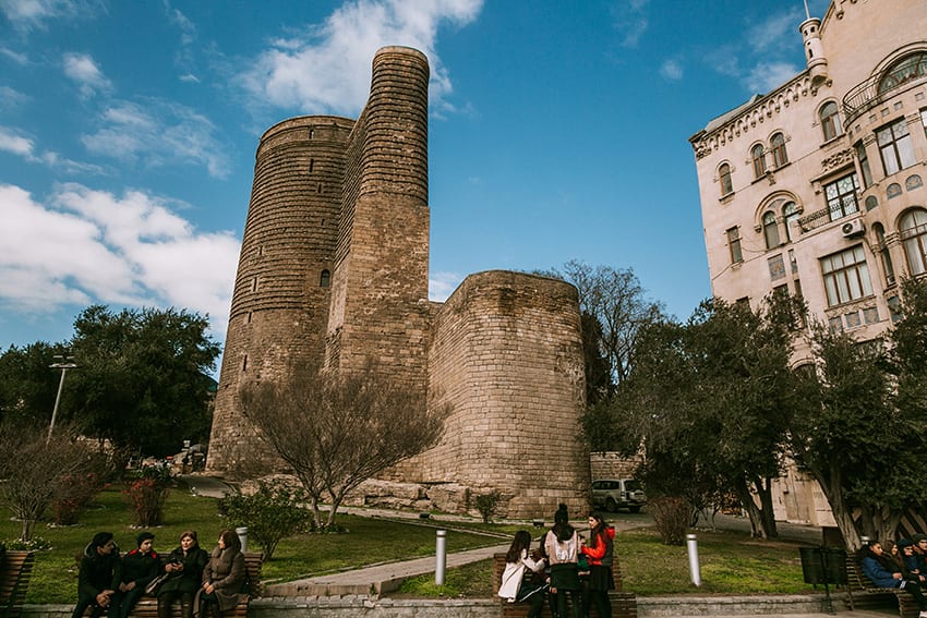 8 Amazing UNESCO Sites in The Middle East - Off the Beaten Track 7 The Maiden Tower in Baku with trees round it and people in the foreground.