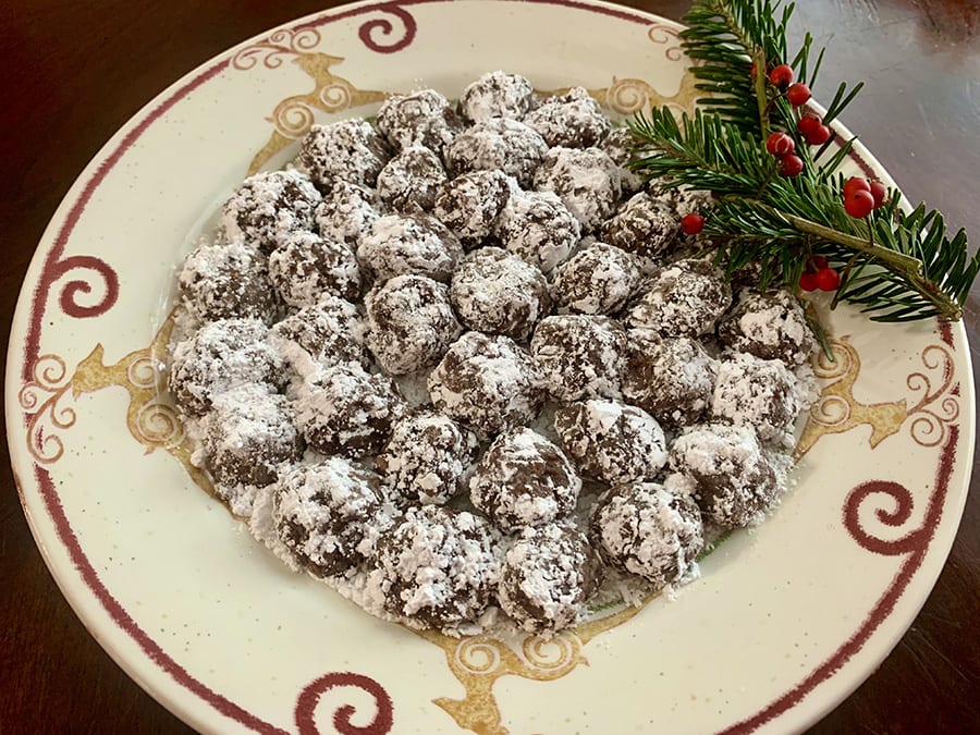Favourite Christmas Bakes to try this year 11 Cream plate with red swirls with a pile of bourbon balls with some holly on the side