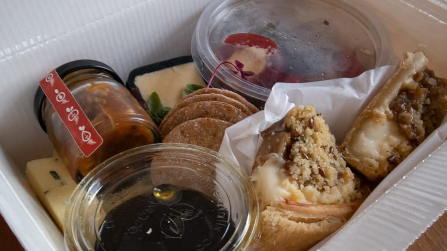 Artisan Bread Baking at the Abergavenny Baker 12 lunch box with fig and camembert tart, cheeses, plastic pot of marinated red peppers, olives and gherkins, pickles and dressing