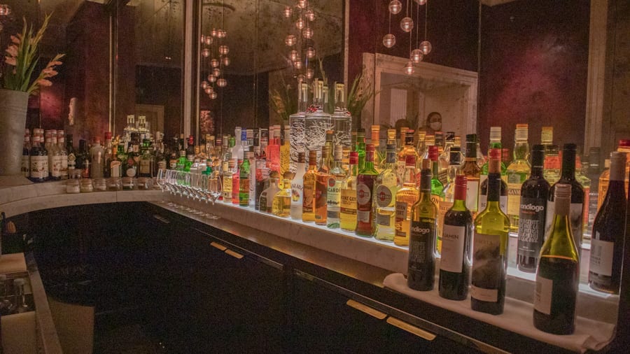 bar with line of bottles reflected in mirror behind