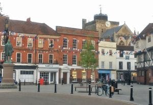 Market square with a Romsey Abbey in the background. There is blue, red and white bunting between the buildings