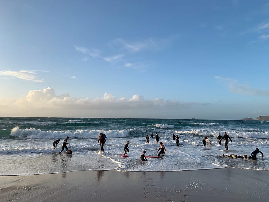 people in wet suits with body boards in the surf in Cornwall