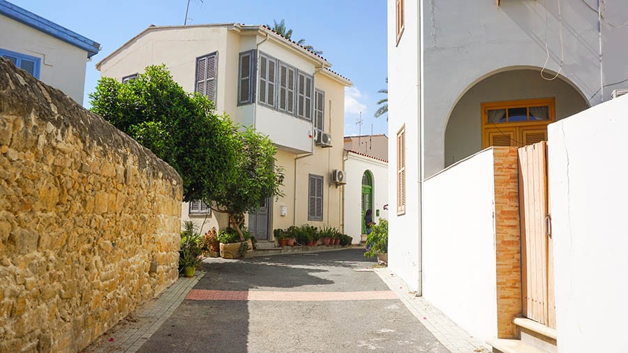 35+ Amazing Hidden Gems In Europe You Must Visit 28 Alley way with white houses to the right and ahead and a caramel coloured brick wall on the leftu