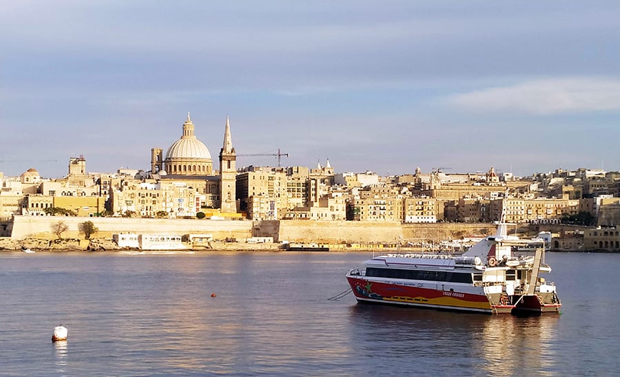35+ Amazing Hidden Gems In Europe You Must Visit 35 The skyline of Valletta, with cream coloured buildings on the shoreline and a domed building in the background. A ferry boat it anchored in the sea