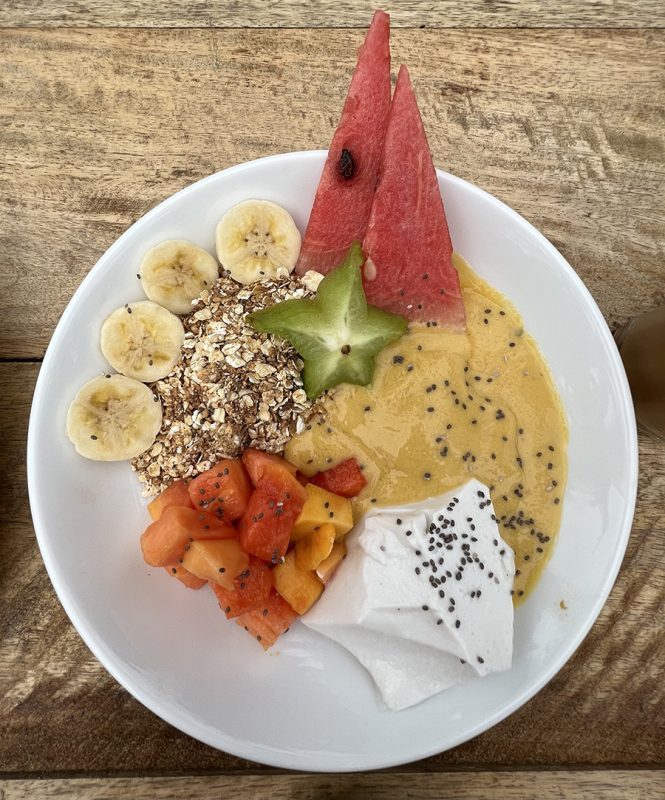 The Best Food In Sri Lanka To Eat (Including 5 Easy Recipes!) 10 white bowl filled with sliced bananas and starfruit, diced guava, triangles of watermelon, muesli, thick fruit smoothie and vegan coconut yoghurt