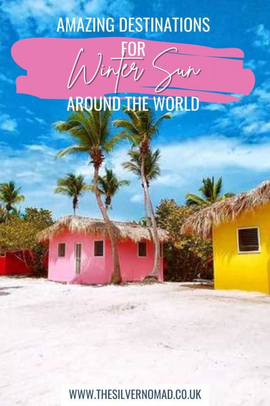 25 Amazing Destinations For Winter Sun Around The World 28 brightly coloured beach shacks with palm trees and Amazing Destinations for Winter Sun around the World written on top