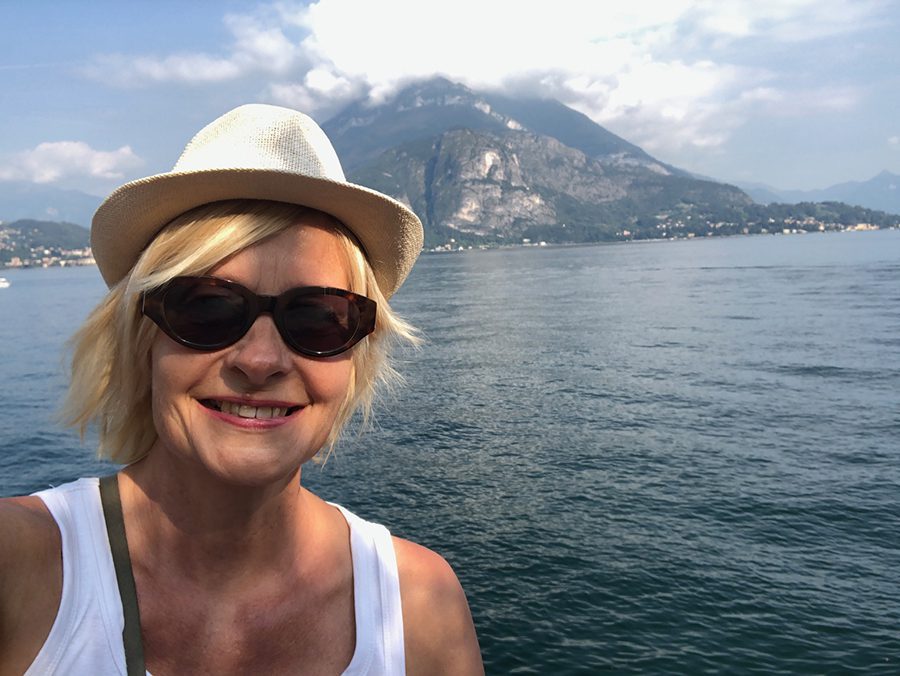 Celebrating 16 Awesome Mature Bloggers In 2021 To Inspire You 5 Sarah Wilson from Life Part2 & Beyond wearing sunglasses and a hat with the sea and mountain behind her