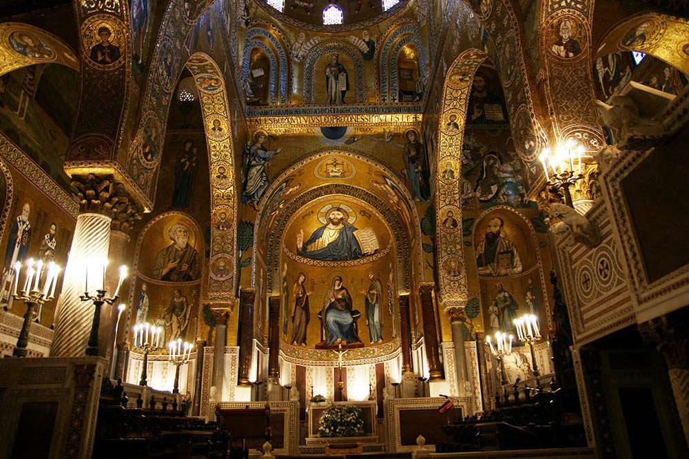 Stunning UNESCO Sites in Italy to discover in 2023 23 the highly ornately decorated Normal Palace with iconography in gold and blue and lit by many candles