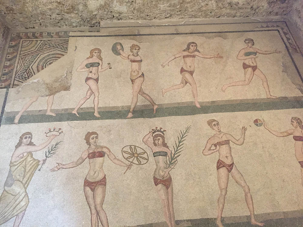 Stunning UNESCO Sites in Italy to discover in 2023 15 mosaics showing tow rows of ladies in red or green tops and red bottoms doing sports