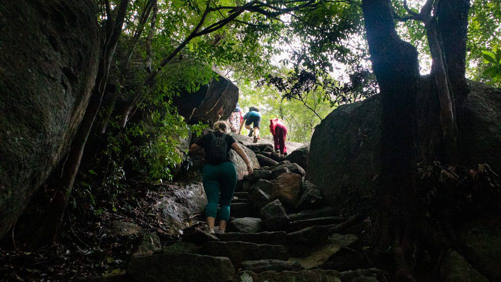 An Eco-Friendly Stay at Wild Glamping Gal Oya, Sri Lanka (2025) 19 three people climbing between the rocks at Rajagala in Sri Lanka
