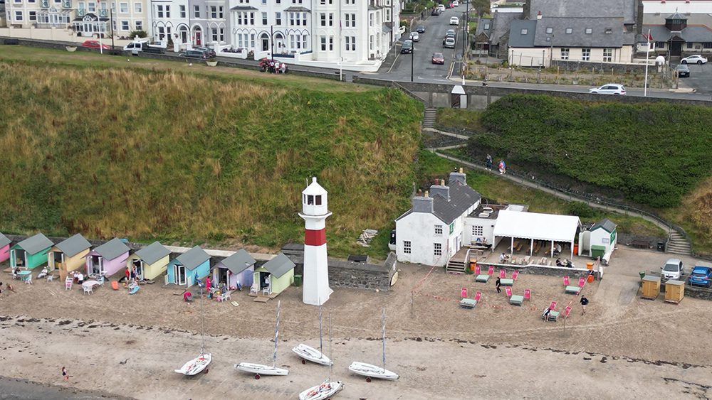 20+ Of The Best Things To Do In Port Erin, Isle Of Man (2023) 22 Foraging Vintners & Noa Bakehouse at the Cosy Nook, Port Erin beach with red and white lighthouse, pastel painted beach huts