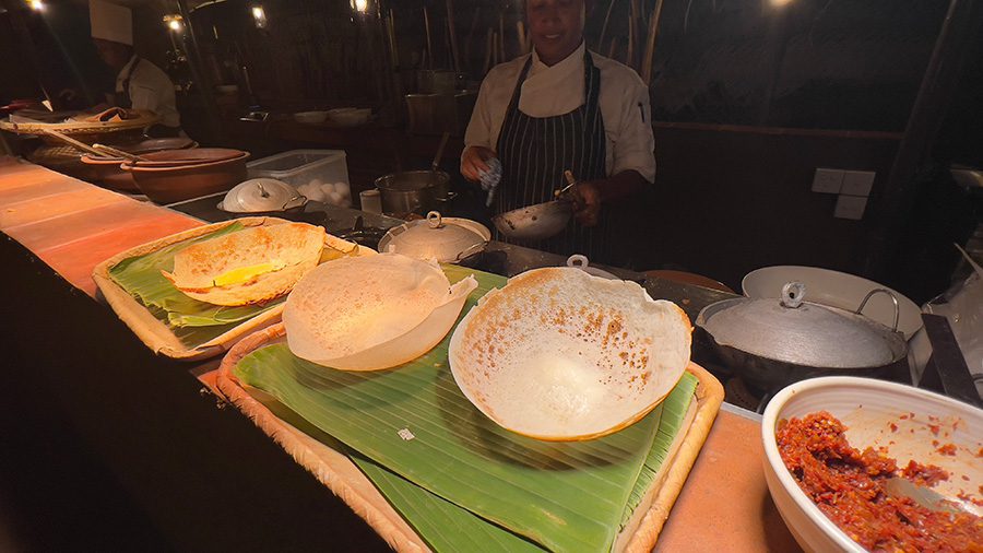 The Best Food In Sri Lanka To Eat (Including 5 Easy Recipes!) 3 bowl-shaped hoppers made from rice flour on a serving bench with the chef standing behind