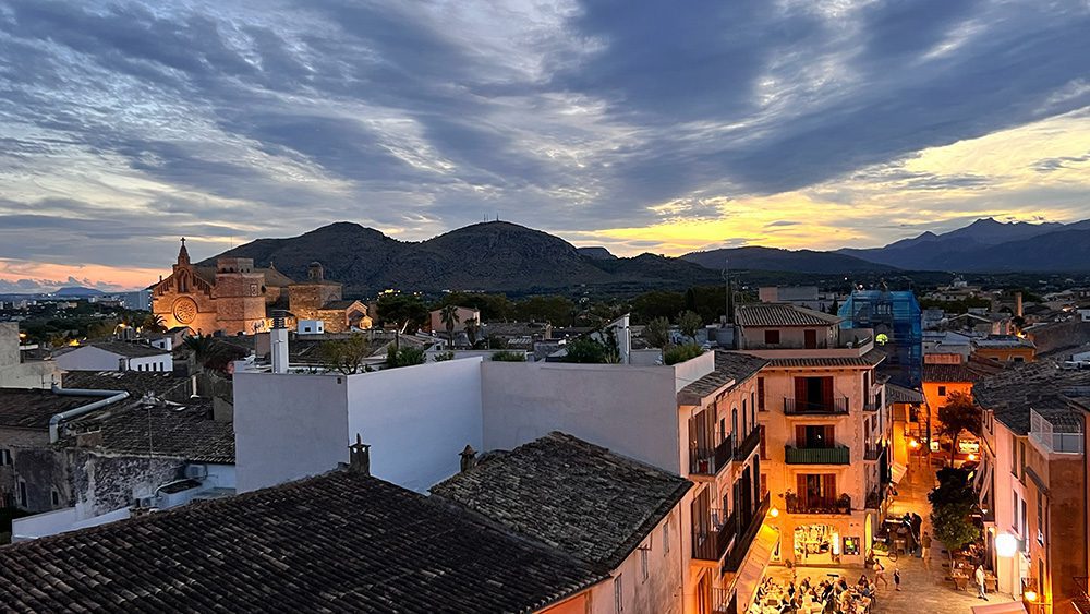 27 Of The Best Things To Do In Alcudia, Mallorca (2023) 5 View of Alcudia Old Town from the roof top with sunset lighting the sky
