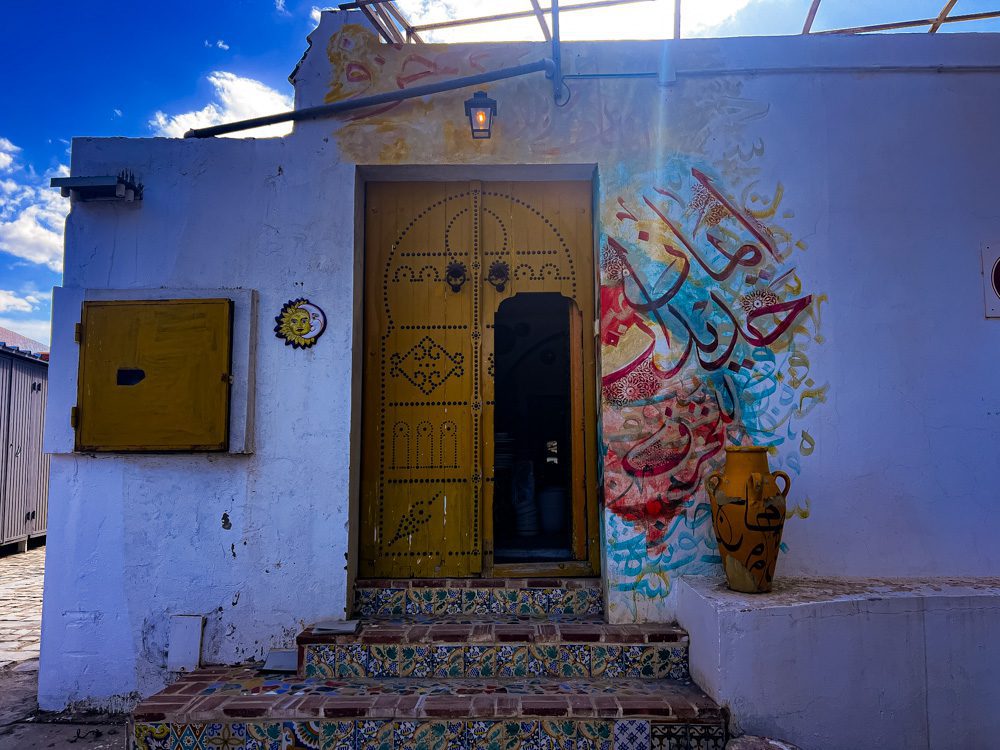 Sawa Taste of Tunisia: Explore the amazing food of Tunisia (2024) 10 The outside of Arceram with a yellow door studdied with black studs. Bright Arabic writing around the door