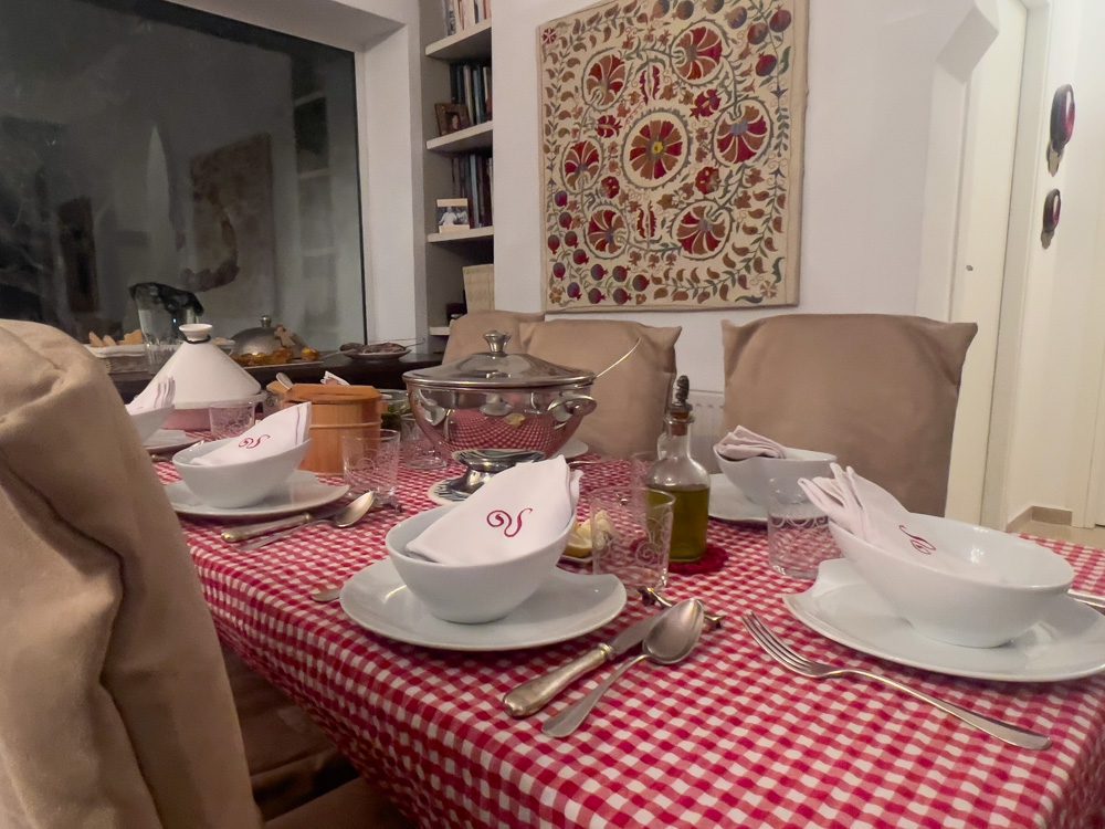 Sawa Taste of Tunisia: Explore the amazing food of Tunisia (2024) 4 table with red gingham table cloth and white crockery. There is a silver pot, olive oil and on the sideboard has more silver platters