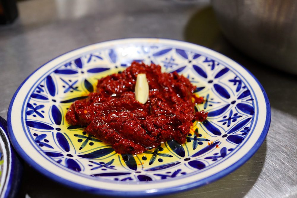 Sawa Taste of Tunisia: Explore the amazing food of Tunisia (2024) 8 the finished harissa with olive oil and garlic on a blue and white plate