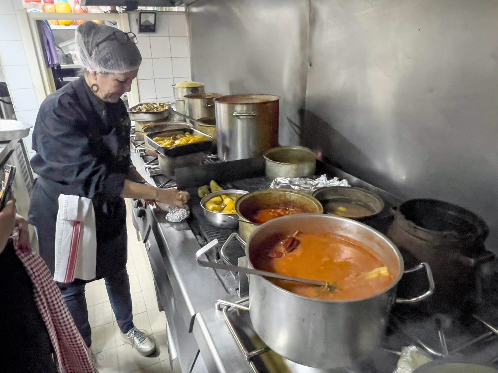 Sawa Taste of Tunisia: Explore the amazing food of Tunisia (2024) 25 Sofie at Dar Sala showing how to prepare Salata machouia in front of the cookers