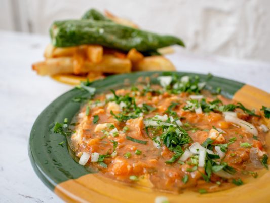 Kafteji - spicy pepper stew served with deep fried pepper and crisp chips served in a green and yellow dish