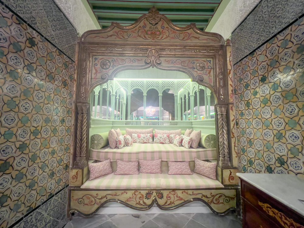 Sawa Taste of Tunisia: Explore the amazing food of Tunisia (2024) 64 One of the sofa areas upstairs at Dar Jaled tiled in greed and yellow with pink and green cushions and ornate frontage and mirrors