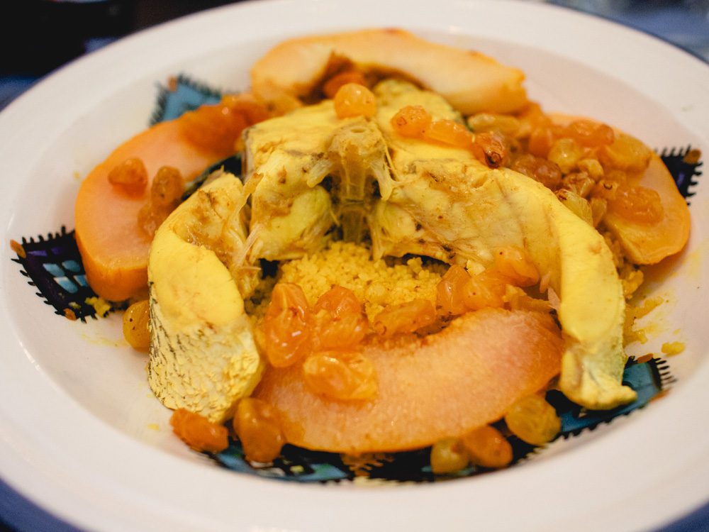Sawa Taste of Tunisia: Explore the amazing food of Tunisia (2024) 27 Fish with couscous, peaches and sultanas on a white and blue plate