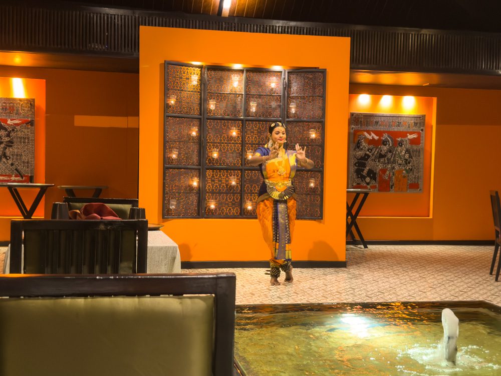 Bharatanatyam Performer in orange and blue, using her hands and face to express emotions and tell the story