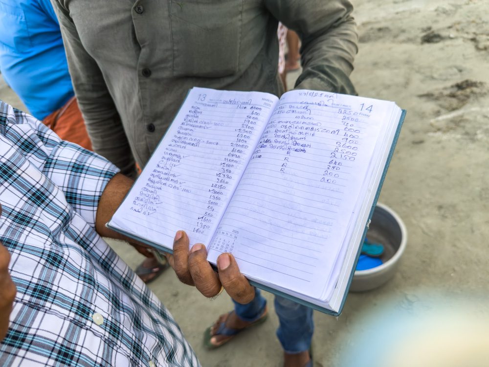Dax holding the book of sales showing what has been sold, weight and price and who to