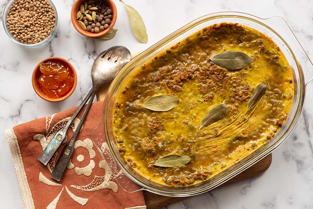 Lentil Bobotie with bay leaves on top and lentils in a bowl next to it - one of the Christmas Treats for Vegetarians