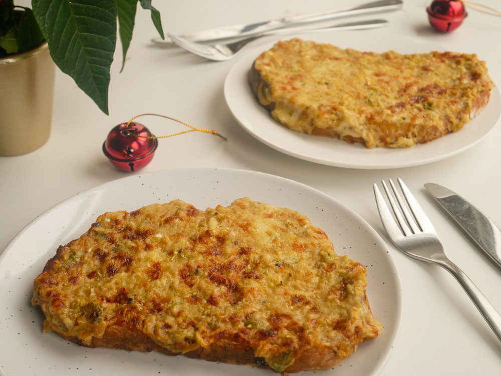 Brussels Sprout Rarebit on white plate with knife and fork and red bell decoration