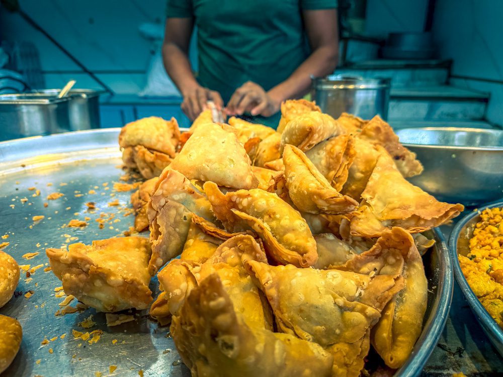 crispy triangular samosas on a silver platter