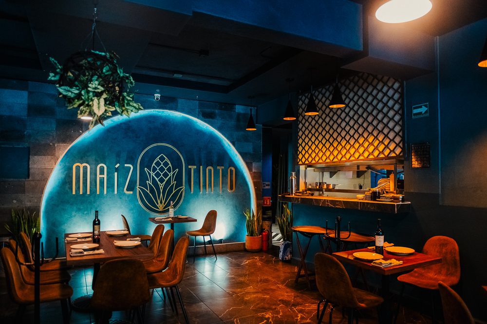 Maiz Tinto one of the best restaurants in Mexico City showing tables set for dinner with roundbacked leather chairs and Maiz Tinto in large letters on the wall